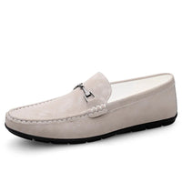 Beige suede slip-on men’s loafers with a metal buckle and black sole, embodying casual elegance
